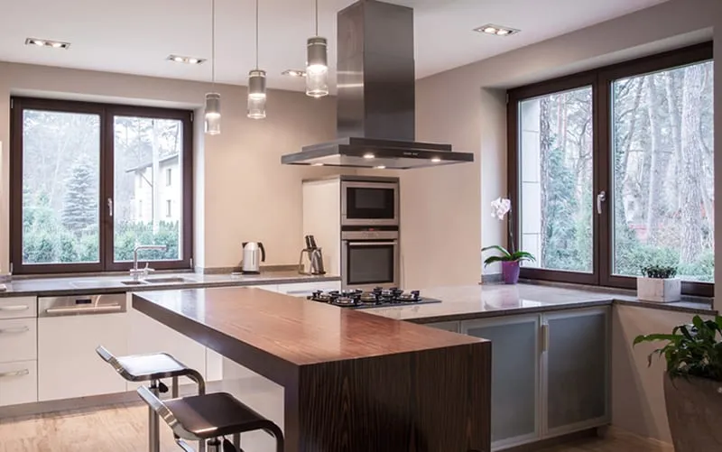Sunlit kitchen with new Okna replacement windows framing a wooded view